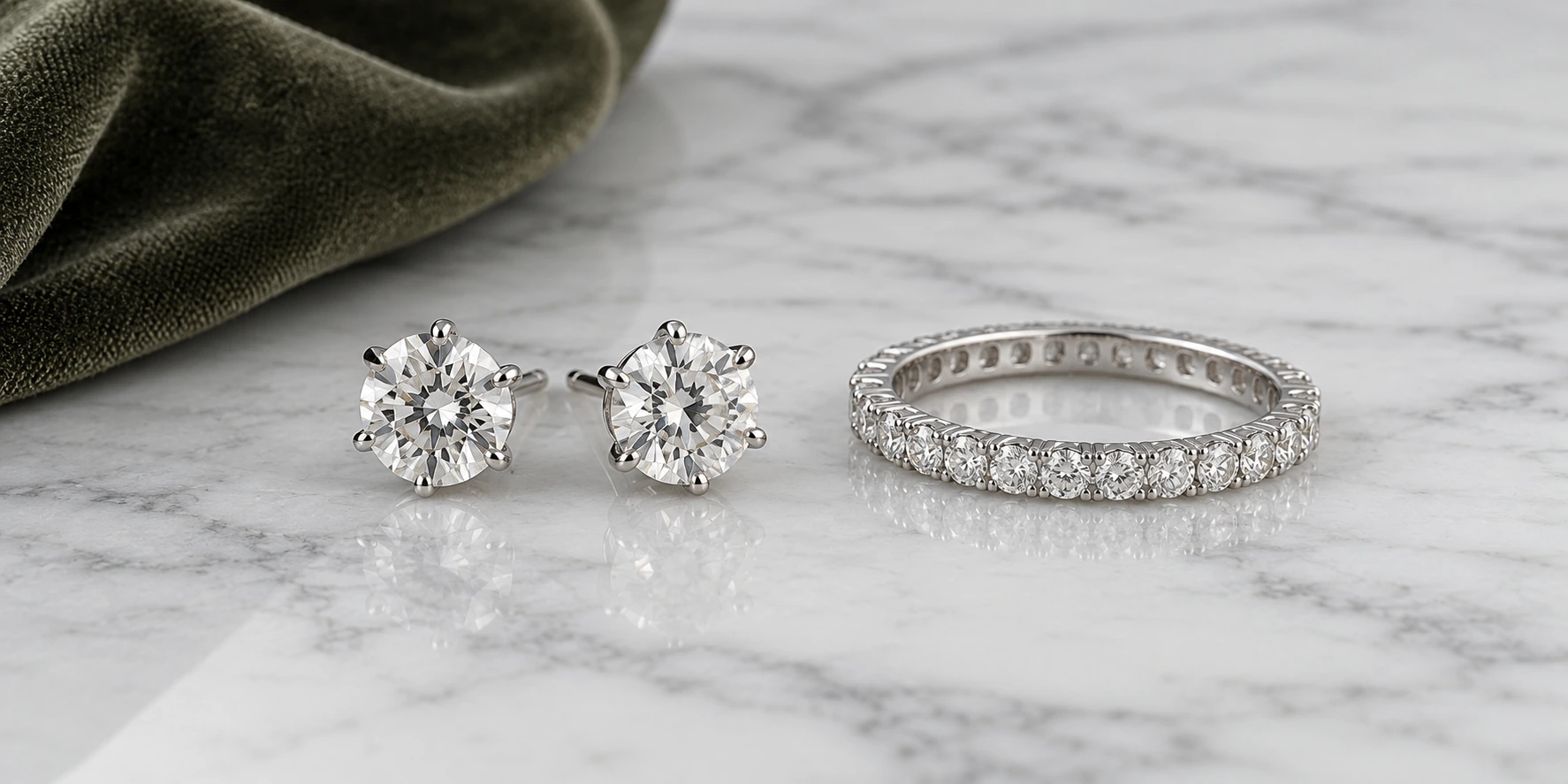 Diamond stud earrings and an eternity band on cool white marble