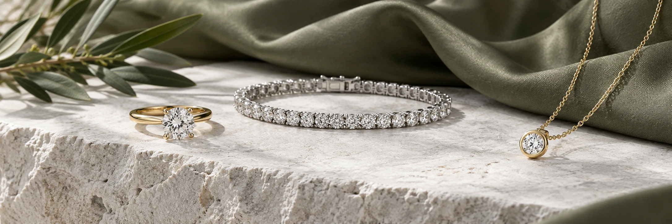 Gold solitaire ring, diamond tennis bracelet and pendant on white stone with olive silk