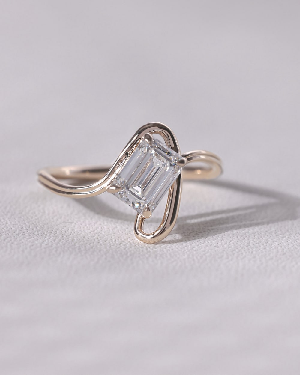 Emerald-cut diamond ring on soft neutral linen